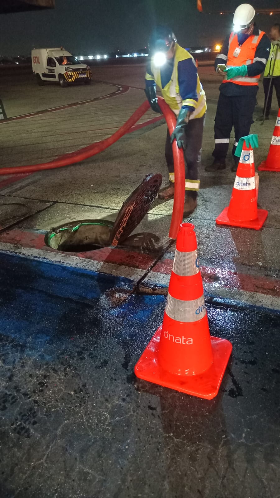 Hidrojateamento em pista de aeroporto com cones de sinalização e EPI completo